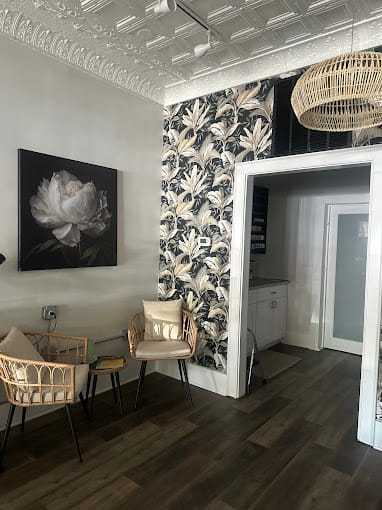 Cozy room with floral wallpaper, wicker chairs, and a peony painting on the wall.