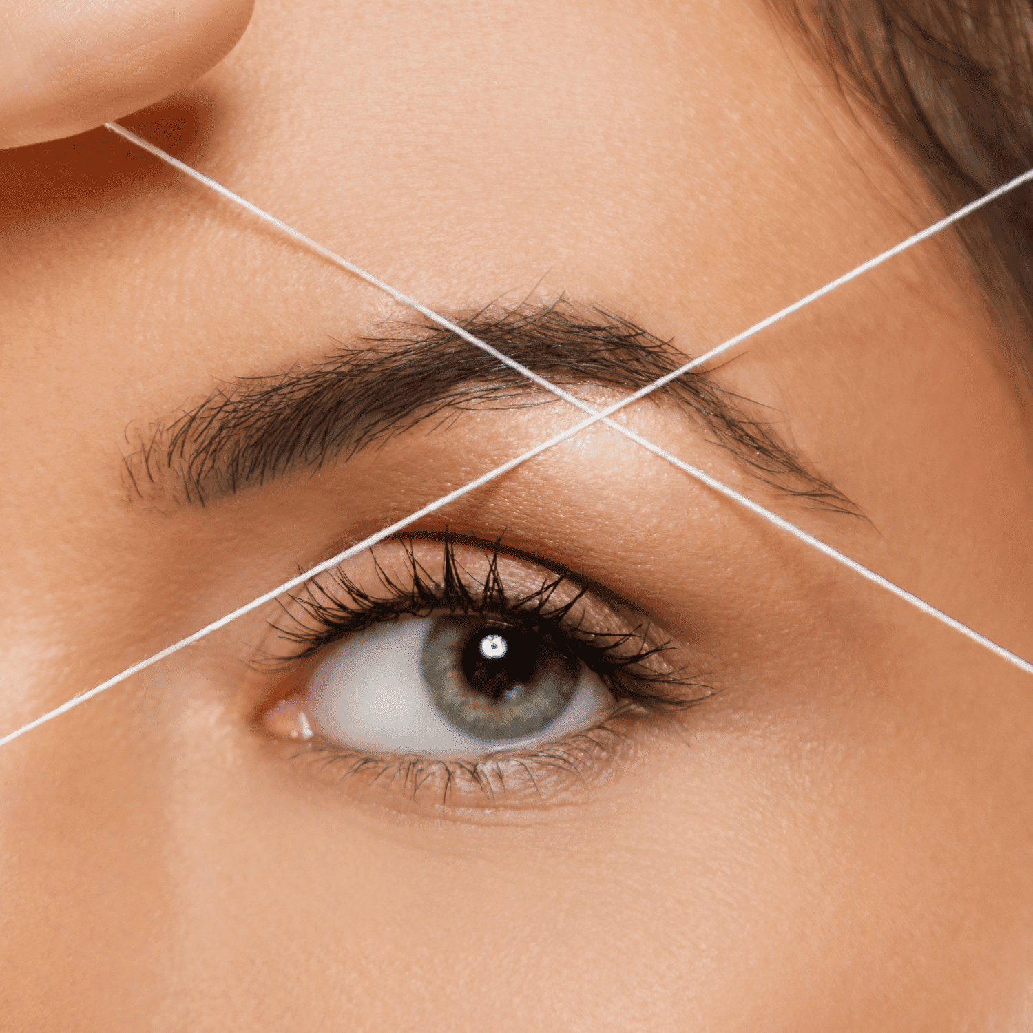 Eyebrow threading process shown up close on a woman's face.
